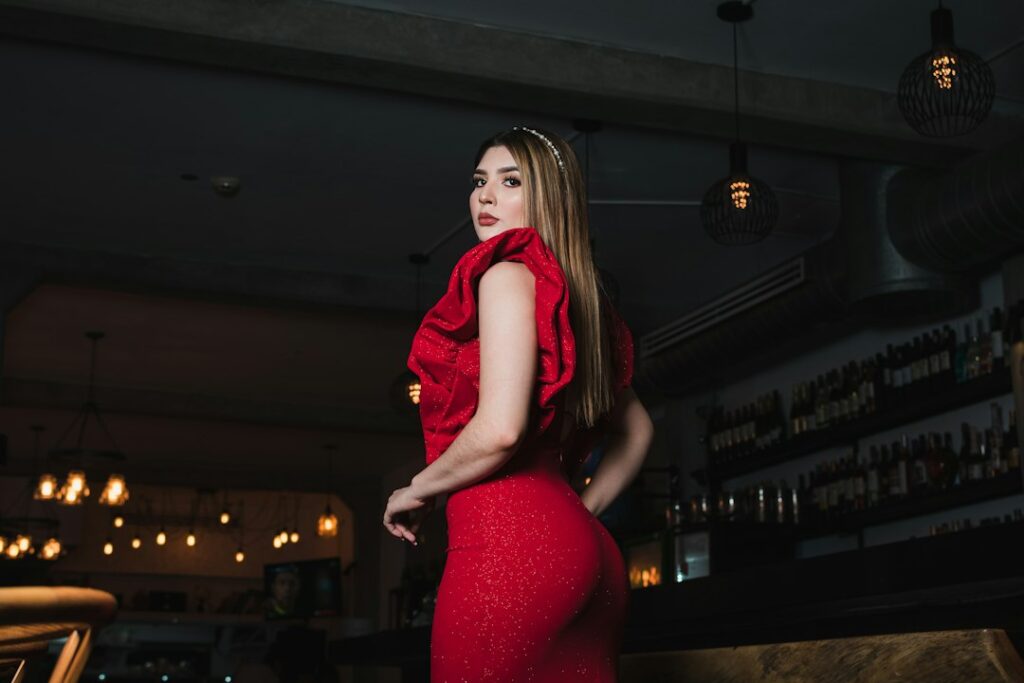 A woman in a red ruffled dress looking over her shoulder in a bar