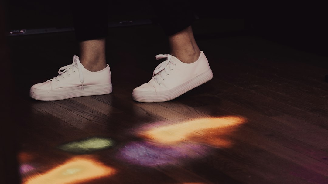 White sneakers worn on a wooden floor
